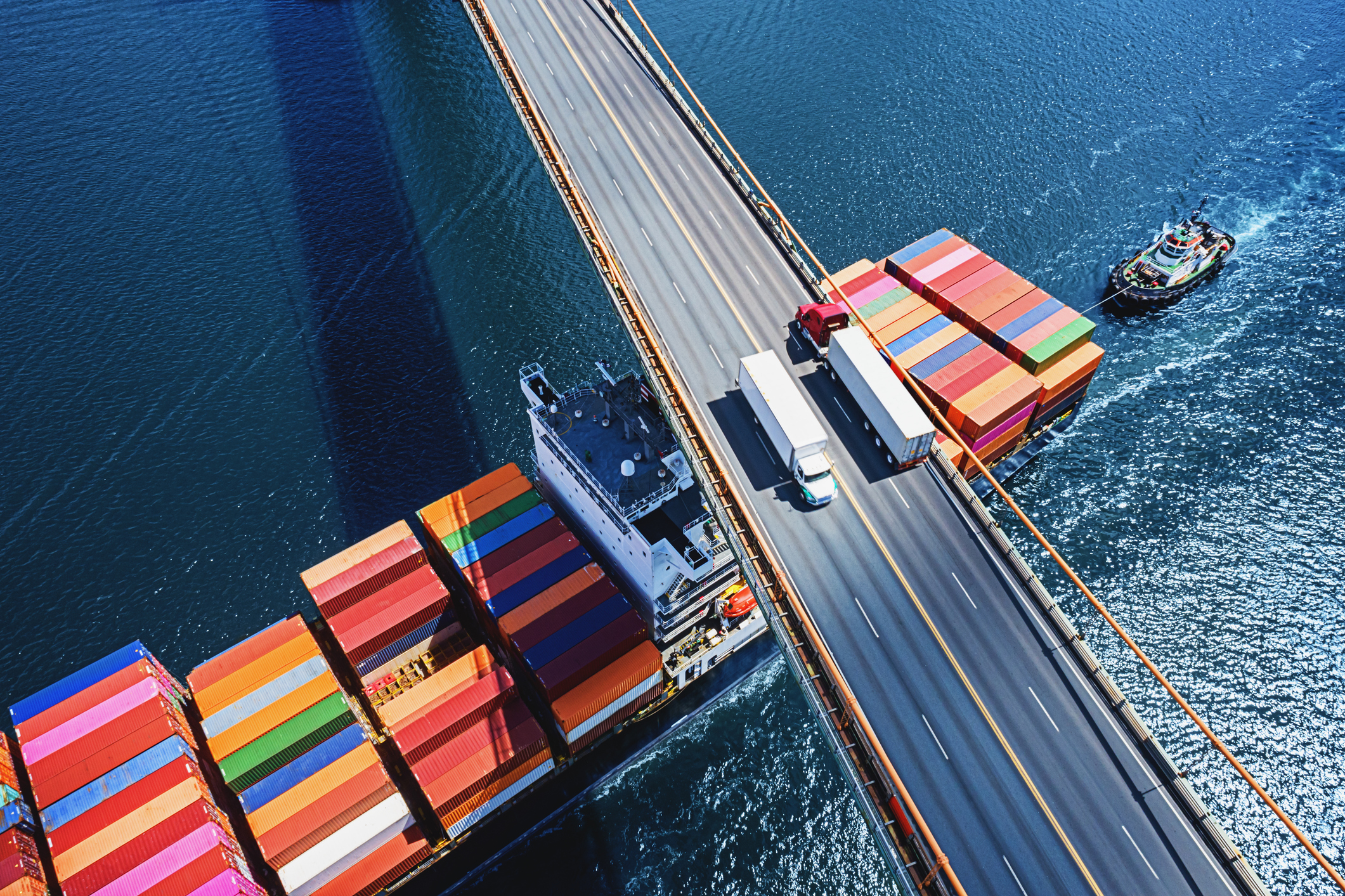 Logistik: Containerschiff unterquert Brücke mit LKWs